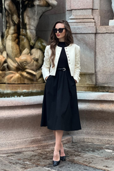 a lady in a black dress with a belt and a white crop jacket
